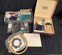 Sewing and crochet accessories organized in boxes including pins, buttons, thread, needles, and an embroidery hoop.