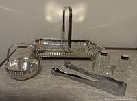 Full set of vintage silver plate serveware showing bowl with handle, rectangular tray, tongs, and salt and pepper shakers.