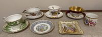 Overview of six teacups, matching saucers, and two trinket dishes arranged on a surface.