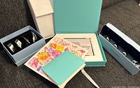 Photo of Tiffany box with matted images and Wedgwood boxes with napkin rings and name card holders.