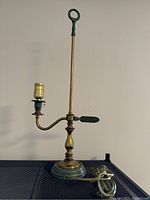 Full view of the vintage brass students lamp with green detailing and the cord coiled at the base.
