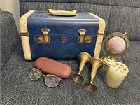 Overview photo showing the vintage sewing kit case, Talbot glasses with case, two brass candlesticks, mini globe, and cream-colored pen holder.