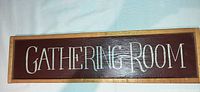 Wooden plaque with 'GATHERING ROOM' in white text on dark background, wooden frame, for wall decoration.