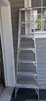 Full view of the 7-foot aluminum step ladder with visible paint splatters on steps and frame.