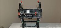 Full view of Black and Decker Workmate 225 portable workbench folded with visible work surface showing measurement grid and clamps with red handles.