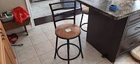 Single bar stool at kitchen island showing black metal ladder back and round tan microfiber seat