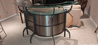 Curved stainless steel and glass standalone bar, side view showing glass top and metal supports