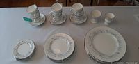 Full lot of Wedgwood Belle Fleur dinnerware displayed on table: stacks of plates by type and cup and saucer sets, plus salt and pepper shakers