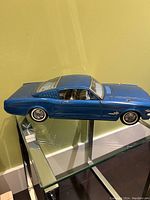 Side view of blue tin plate toy car showing 1960s Ford Mustang body shape and detailed wheels.