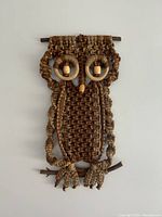 Full view of 1970s handmade macrame owl wall hanging made from brown rope and wooden elements.