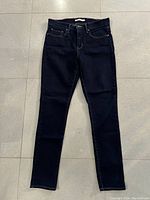 Front view of dark blue Levi's 311 shaping skinny jeans laid flat showing full length and skinny fit.