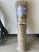 Front view of the new roll of burlap plant protection barrier in its plastic wrapping showing the label with brand and product description.