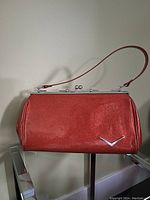 Front view of red glitter purse with strap, showing retro automobile-inspired style and metallic chevron detail.