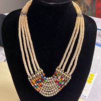 Front view of the 4-strand beaded necklace showing multi-colored and shell beads with decorative pattern in the center.