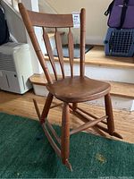 Full view of the antique solid wood arrow back rocking chair showing seat, rockers, and backrest.