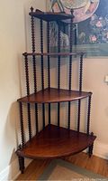 Full view of the antique four-tier corner whatnot shelf showing its height, turned spiral spindle supports, and triangular shelves.