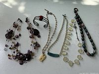 Top view of complete jewelry lot showing cuff bracelet and five necklaces arranged in a row
