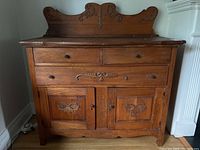 Full view of the antique sideboard showing three drawers across the top, two cabinet doors below, and carved wooden details.