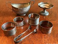 Full lot view; oval sugar bowl, pedestal dish, four napkin rings and sugar tongs