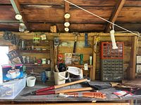 Full view of wooden shed interior counter and wall with tools hanging and placed on surface