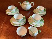 Overall view of the tea set showing teapot, four teacup and saucer sets with plates, creamer, and sugar bowl