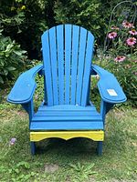 Front view of the blue wooden Muskoka chair showing its wide armrests, vertical slatted back, and yellow painted front lower rail