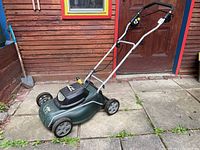 Side profile of green Yardworks electric lawn mower showing the 14-inch deck, silver handlebar, and wheels.