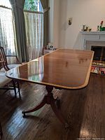 Full view of extended wood dining table assembled with two removable leaves, showing wood grain and two-tone border