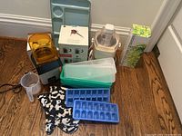 Wide view of various kitchen items including Bodum coffee set box, electric juicer, popcorn popper, Tupperware containers, mugs, ice trays, measuring cup, oven mitts, herbal tea box