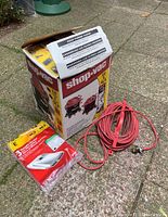 Image of the Shop Vac cardboard box with an extension cord and pack of replacement filters placed on ground.
