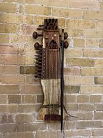 Front view of sarangi with bow hanging against brick wall