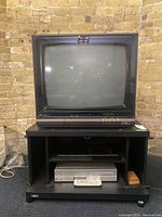 Front view of the 25-inch NEC tube television model CT-2505A on a black stand with the Philips VCR and remote in front.