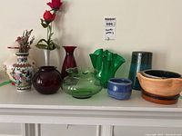 Full view of the vases and pottery on a shelf, showing their shapes, colors, and relative sizes.