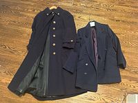 Full-length navy wool coat by Irving Samuel with buttons and a belted waist, open to show lining, displayed on wooden floor.