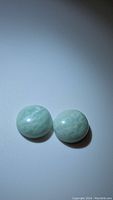 Two round natural amazonite cabochon gemstones on a plain background, showing light green-blue color and marbled patterns
