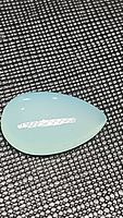 Close-up photo of a smooth pear-shaped, translucent blue-green chalcedony cabochon gemstone on black mesh background.