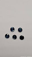 Five natural blue sapphire gemstones laid flat, showing color and size.