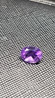 Close-up photo showing the oval cut deep purple amethyst gemstone on a textured background.