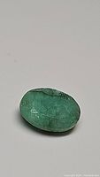 Close-up photo of the oval cut emerald gemstone showing color and inclusions.