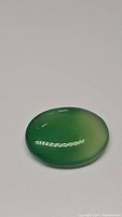 Photo of green onyx oval cabochon gemstone showing smooth polished surface and rich green color