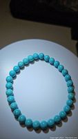 Full view of natural turquoise bracelet arranged in circular shape, highlighting evenly sized robin's egg blue beads on stretchy string.