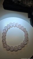 Photo of natural rose quartz chunky bead bracelet showing soft pink round beads strung on elastic band under direct light.