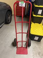 Front view of red metal hand truck dolly showing frame and tires.