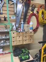 Wooden workbench surface with two EGO batteries and charger beneath wall-mounted tool storage.