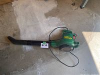 Full side view of Super Weed Eater 2580 leaf blower with power cord and blower tube attached laying on concrete surface