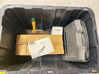 Open plastic bin showing Makita belt sander box, manual, paint scraper, Porter-Cable case and rotisserie motor box