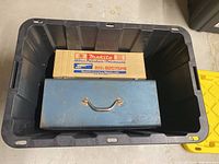 Plastic storage bin containing a Makita polisher box and a blue metal toolbox.