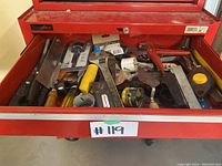 Photo showing open top drawer of red Husky rolling tool chest packed with various hand tools including saws, wrenches, screwdrivers, measuring tape, and more.