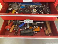 Top drawer with wooden handled rolling tool, Ridgid socket wrench set, and various small hand tools and hardware parts.