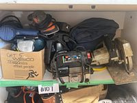 Shelf with assorted power tools and cardboard box with tools inside